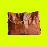 Bolsa femenina de cuero en color marrón, con cortes cuadrados y asa dorada en forma de cadena con detalle verde, sobre fondo verde limón