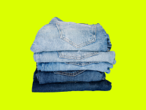 Cuatro pantalones jeans doblados y organizados uno encima del otro, en fondo verde limón